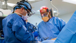 Two doctors in operating room performing surgery on patient.