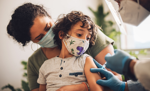 Child wearing a mask receiving a vaccination