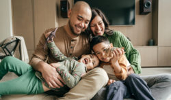 Family of four laughing on a couch.