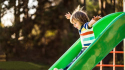 Young boy going down a green slide