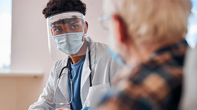 Resident wearing PPE talking with patient