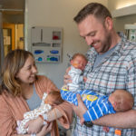 Parents holding three babies in NICU