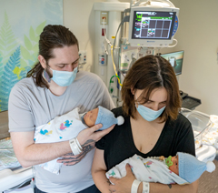 Parents holding twins in NICU